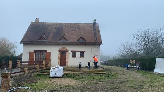 Maison à trois lucarnes : nettoyage de la toiture en petites tuiles plates, couvreur sur le toit et matériel au pied de la façade, secteur de Juilly